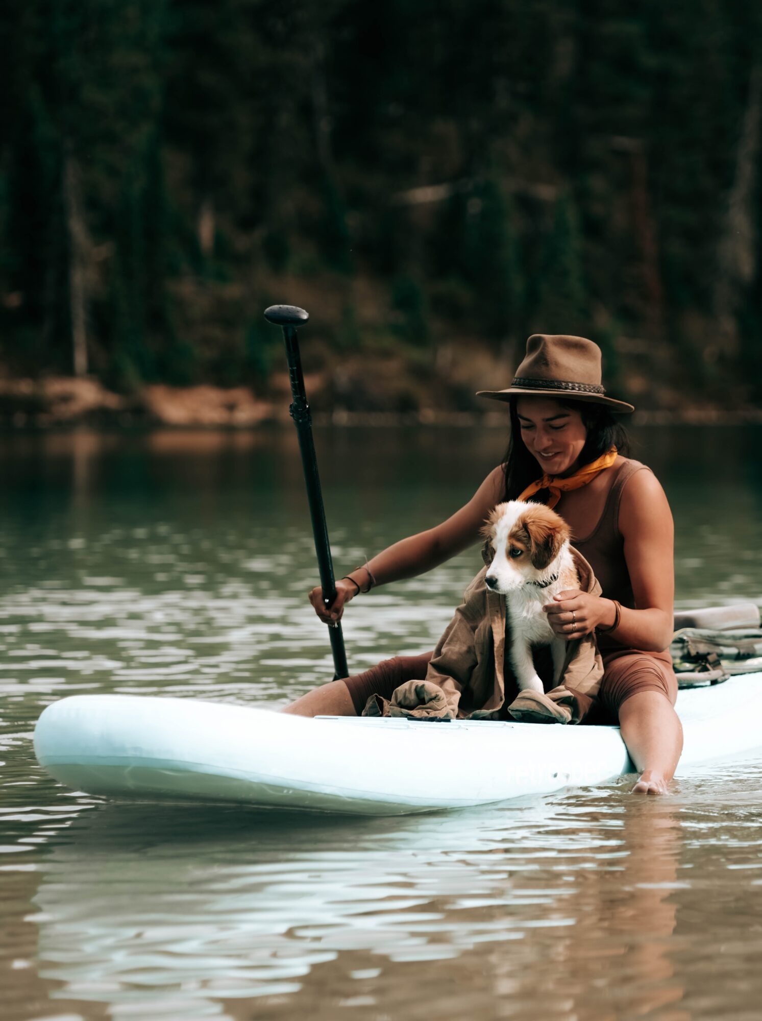 Woman and dog sitting on a paddle board